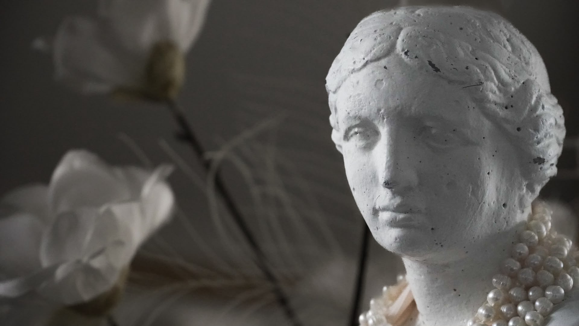 Klassiek wit sculptuur met parels en magnoliabloemen in zacht licht